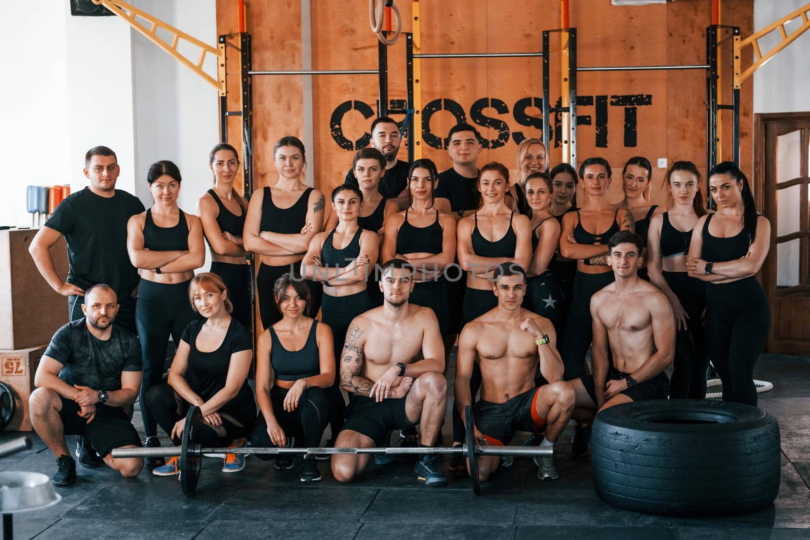 Group of young sportive people have crossfit day indoors in gym.