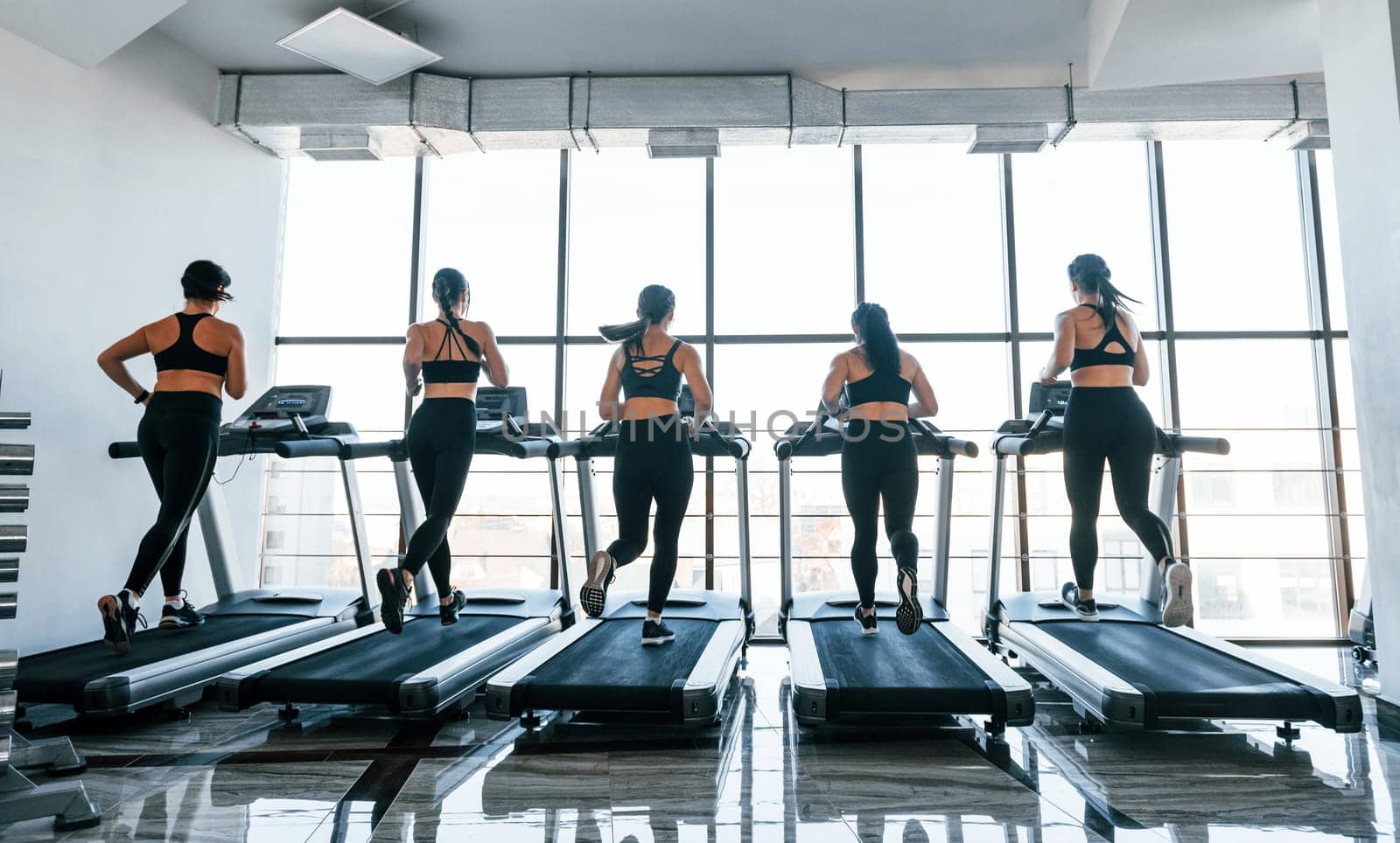 Running on a treadmill. Group of young sportive people have crossfit day indoors in gym.