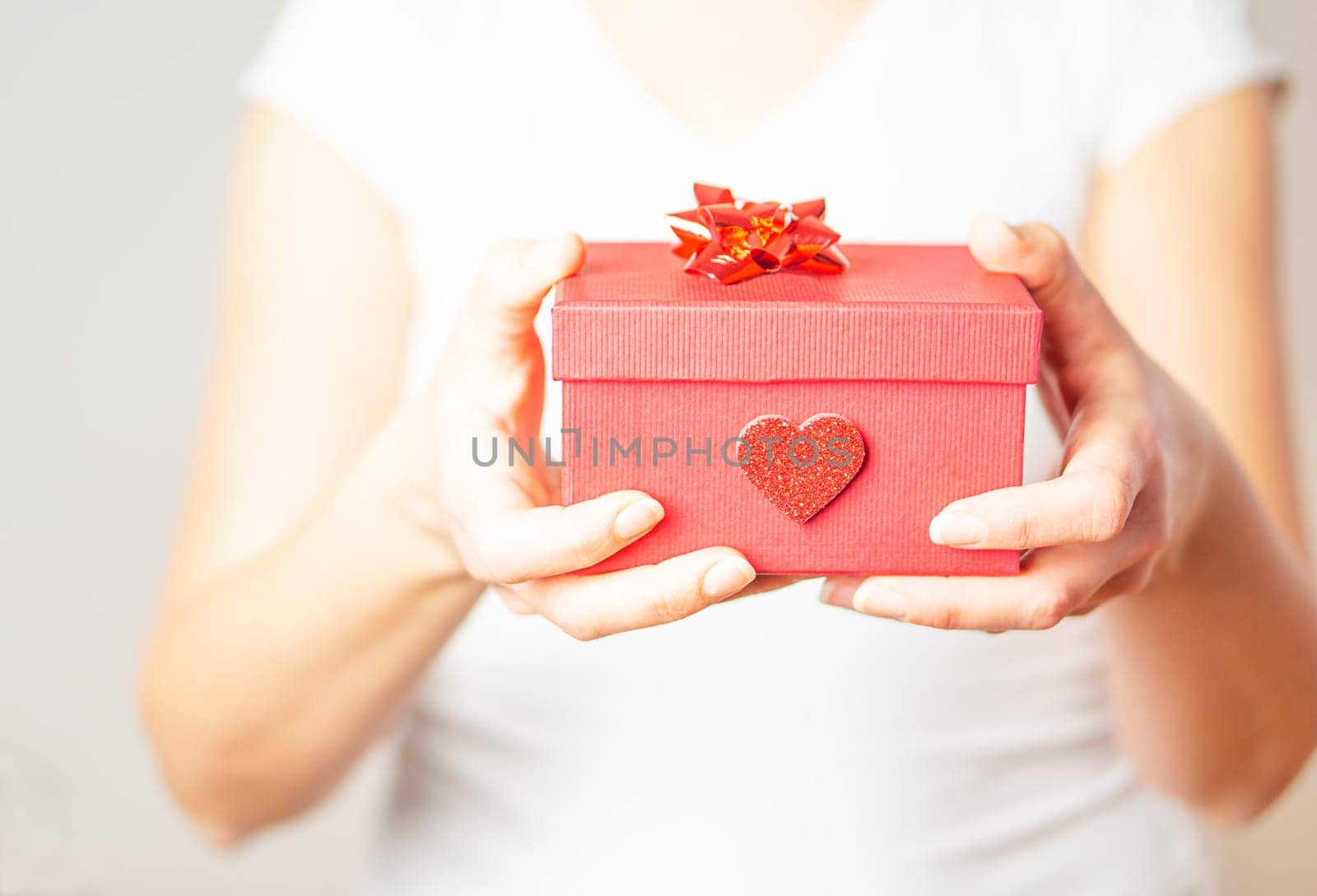 Close up shot of the female hands holding a small gift in a red box. Valentine gift. High quality photo.