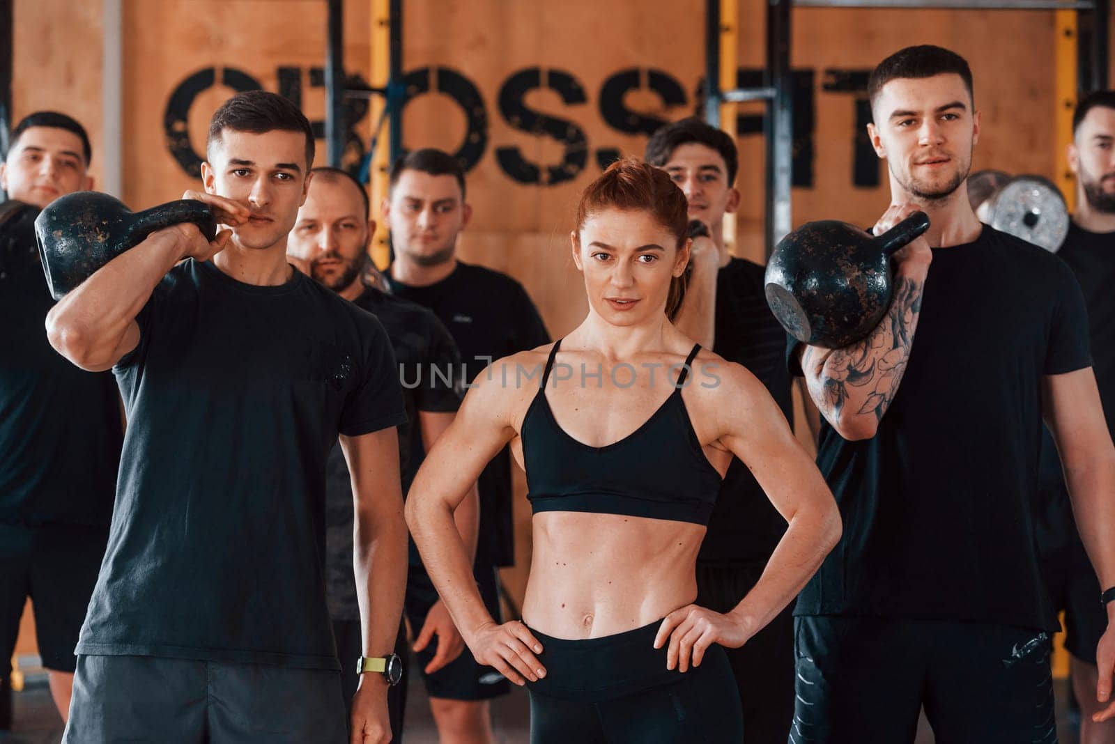 Posing for a camera. Group of young sportive people have crossfit day indoors in gym.