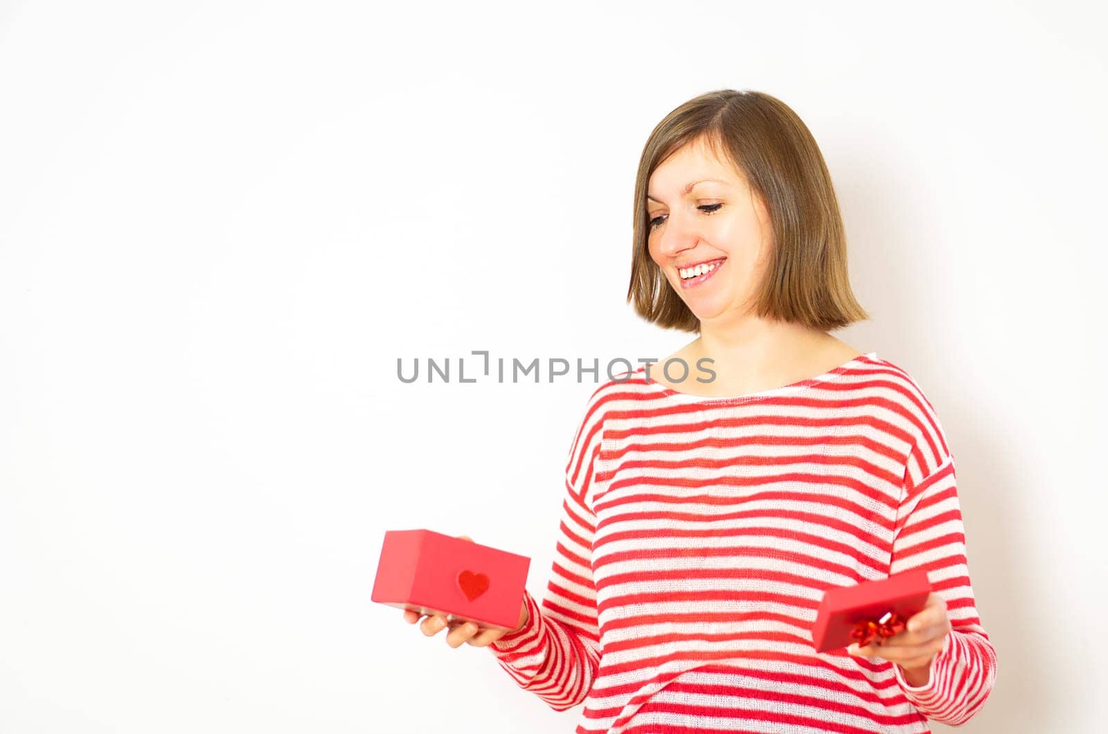 Happy smiling women in red and white shirt with a red gift box on the white background. Happy valentines day.