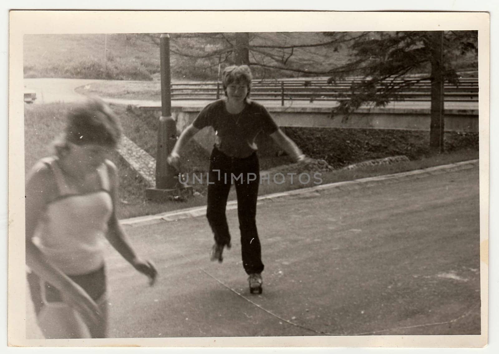 Retro photo shows girl who rides on roller skates. Black and white vintage photography. by roman_nerud