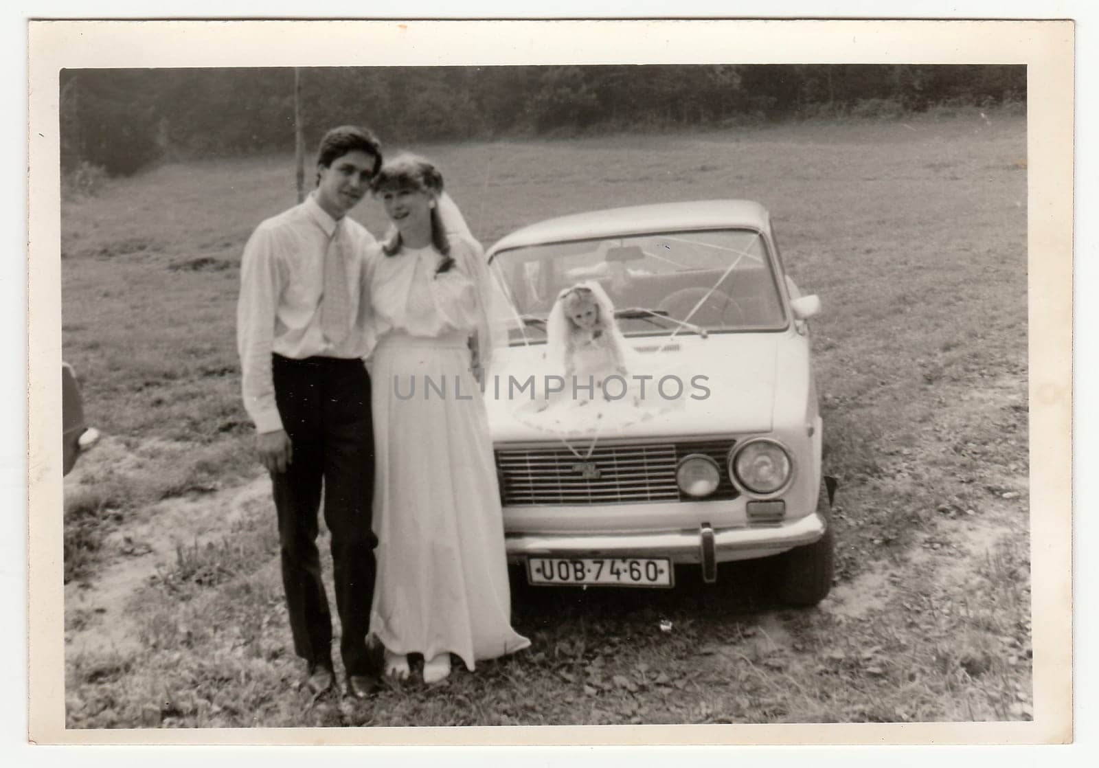 THE CZECHOSLOVAK SOCIALIST REPUBLIC - CIRCA 1970s: Retro photo shows newlyweds and wedding car. Black and white vintage photography.