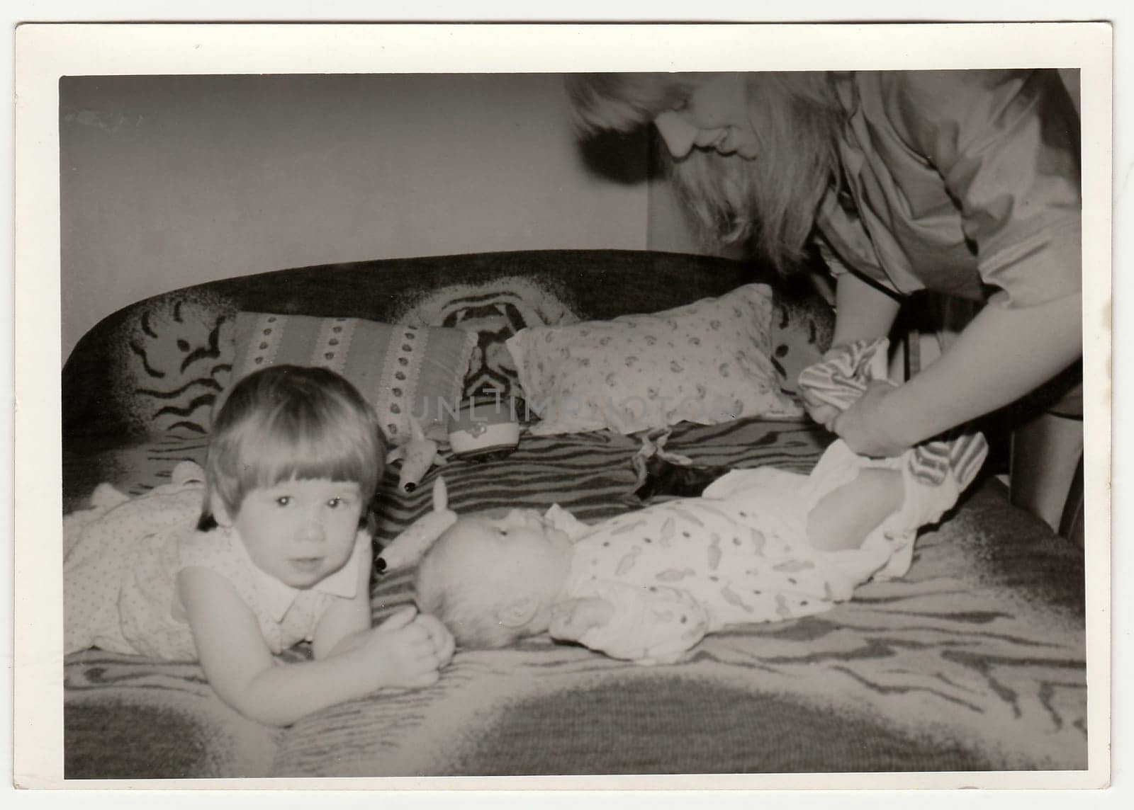 THE CZECHOSLOVAK SOCIALIST REPUBLIC - CIRCA 1970s: Retro photo shows mother puts on the baby. Black and white vintage photography.