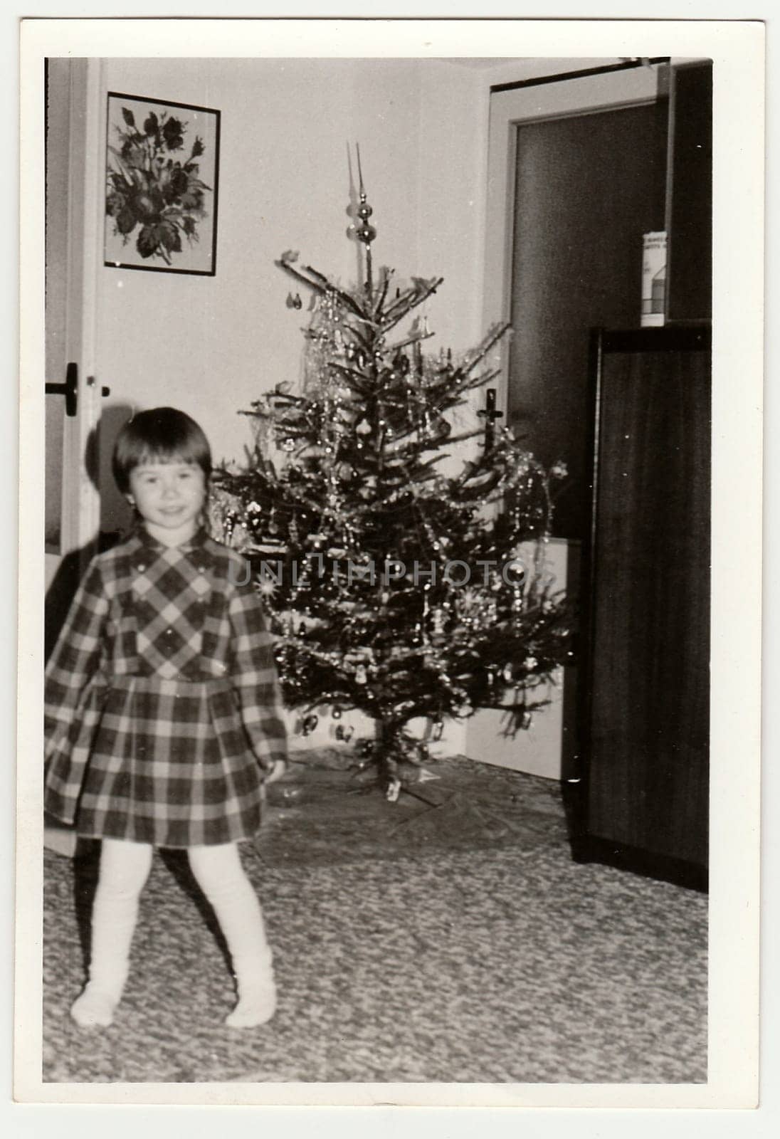 THE CZECHOSLOVAK SOCIALIST REPUBLIC - CIRCA 1970s: Retro photo shows small girl during Christmas. Christmas tree is on background. Black and white vintage photography.