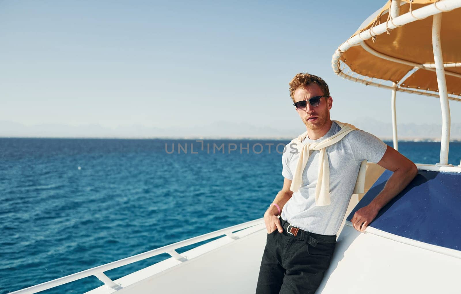 Young male tourist is on the yacht on the sea. Conception of vacation by Standret