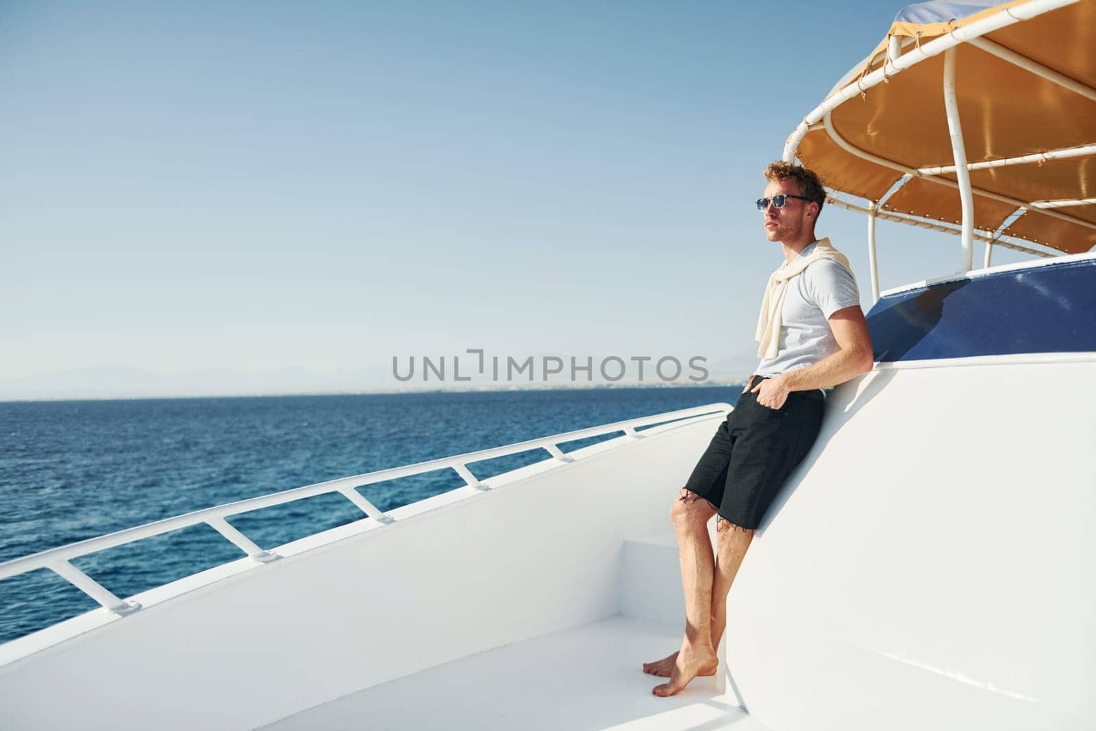 Young male tourist is on the yacht on the sea. Conception of vacation.