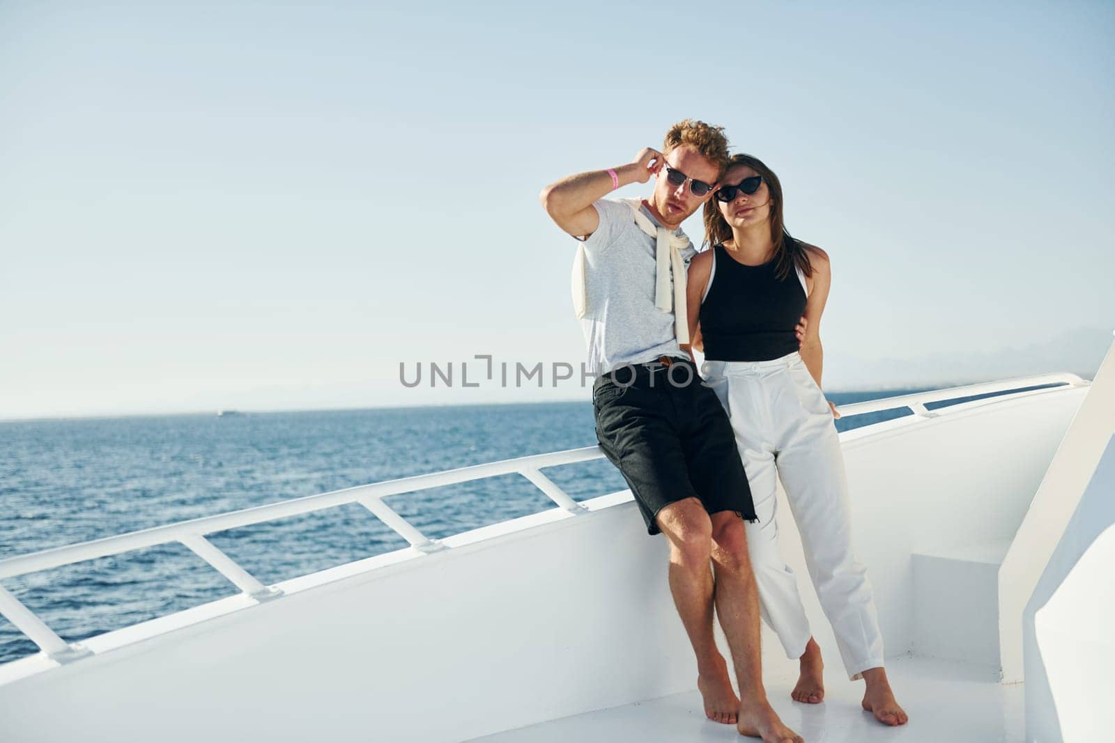 Cheerful young couple standing on the yacht on the sea. Conception of vacation.