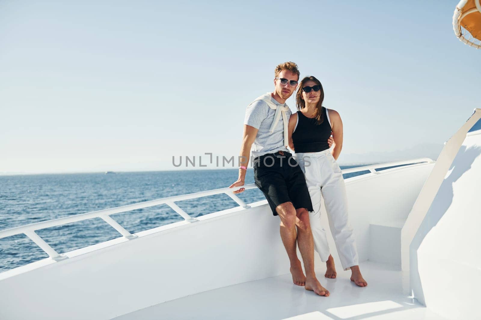 Cheerful young couple standing on the yacht on the sea. Conception of vacation.