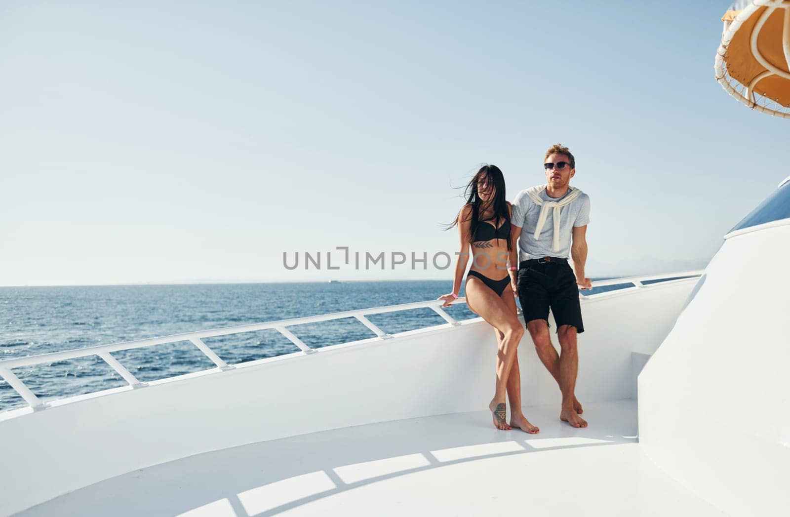 Cheerful young couple standing on the yacht on the sea. Conception of vacation.