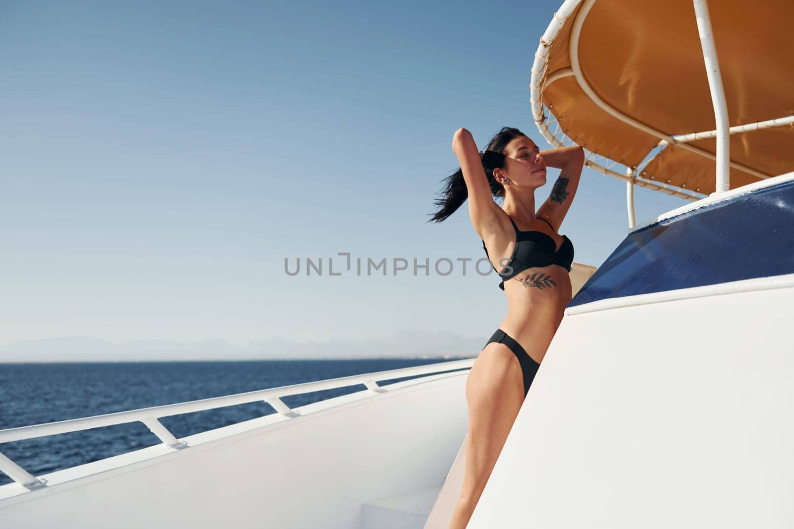 Young brunette in bikini is on the white yacht on the sea. Conception of vacation.