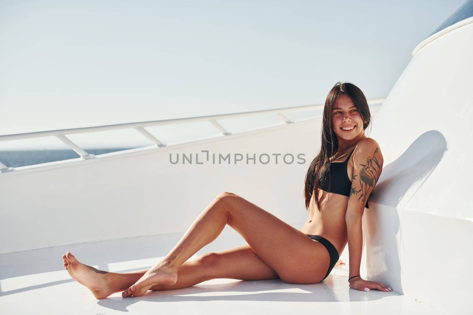 Young brunette in bikini is on the white yacht on the sea. Conception of vacation.