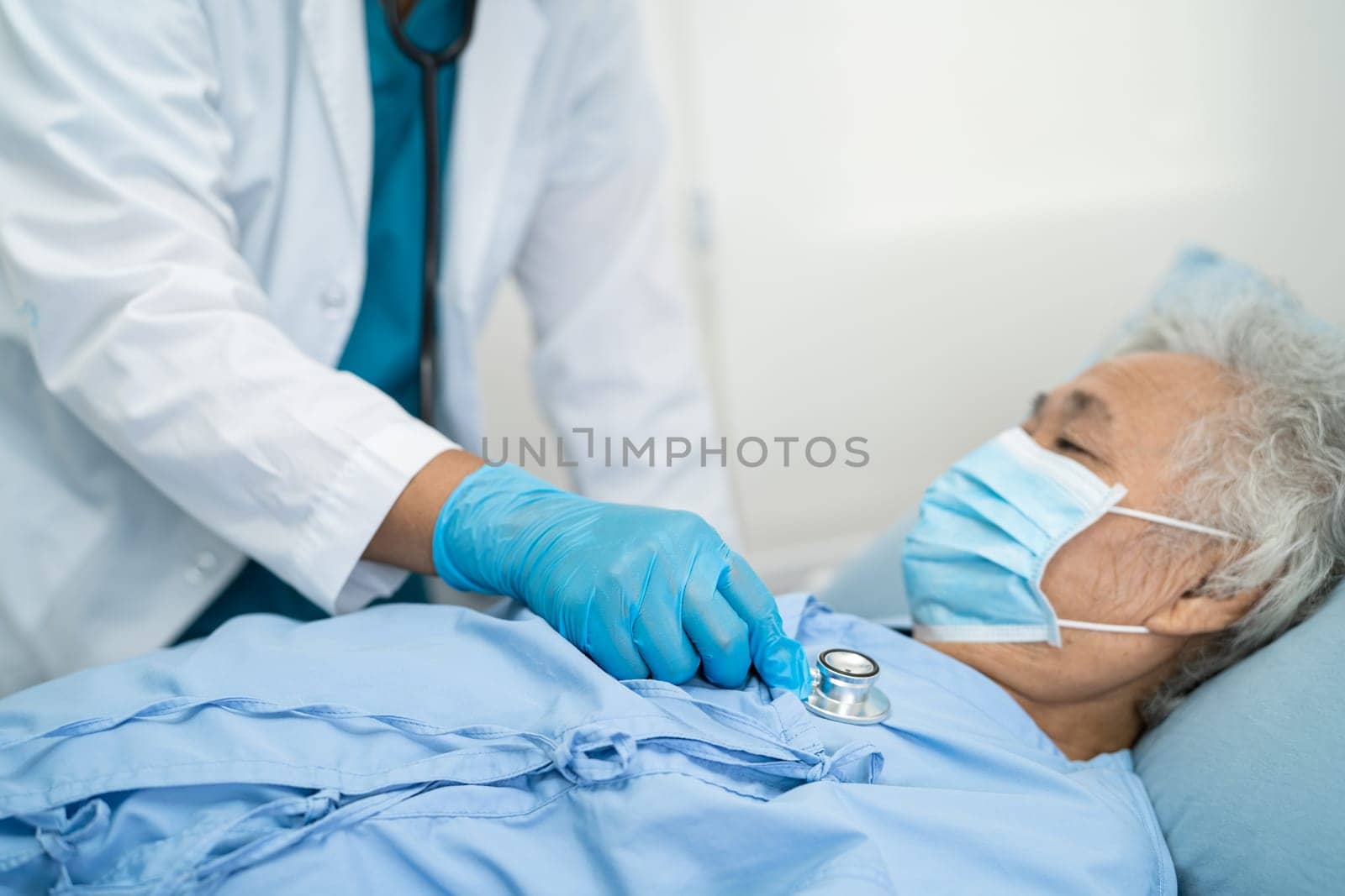 Doctor checking Asian senior woman patient wearing a face mask in hospital for protect Covid19 Coronavirus.