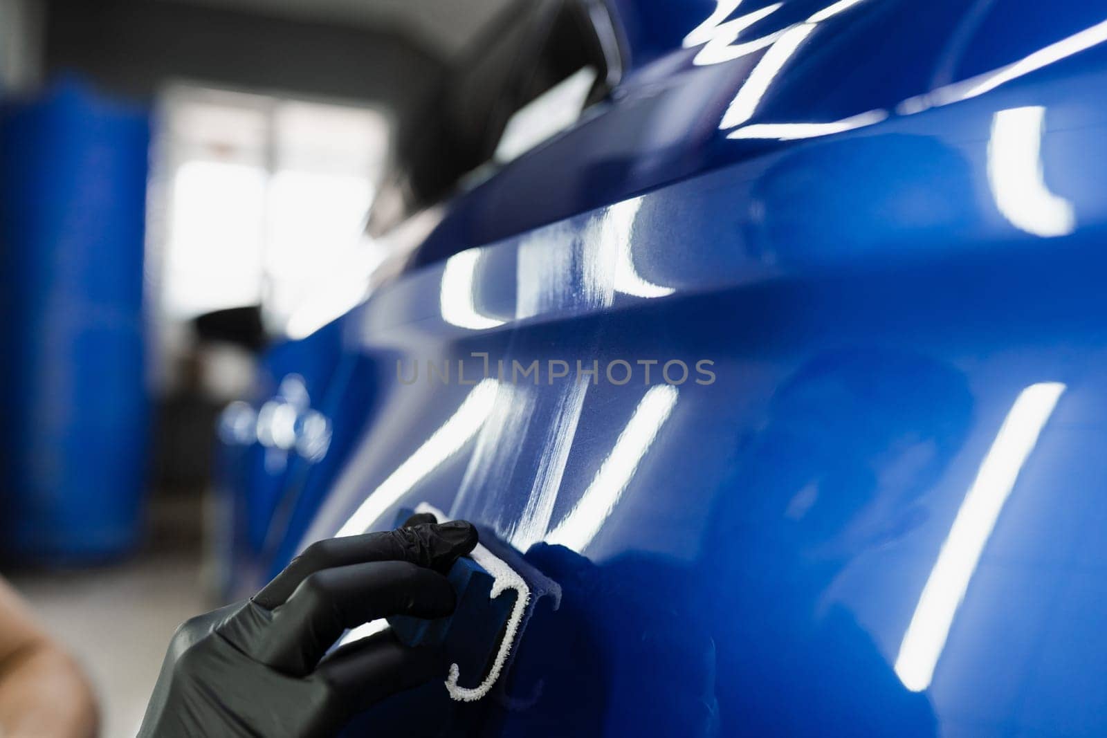 Close-up hand applying of nano ceramic protective coat to protect car from scratches. Process of apply ceramic layer on body car using sponge in detailing auto service