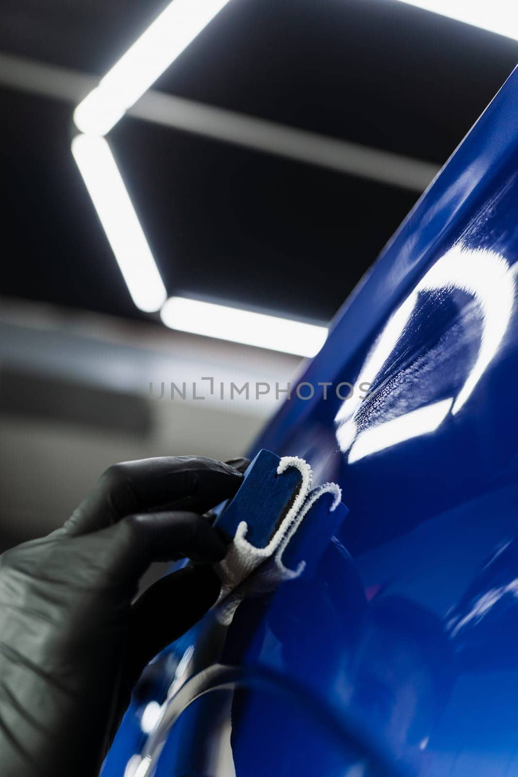 Close-up hand applying of nano ceramic protective coat to protect car from scratches. Process of apply ceramic layer on body car using sponge in detailing auto service
