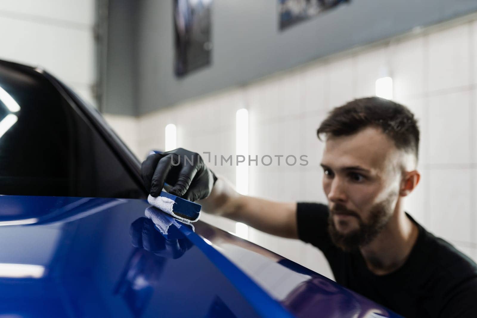 Detailing service worker applies ceramic protective liquid on car. Hand applying of nano ceramic protective coat to protect car from scratches. by Rabizo