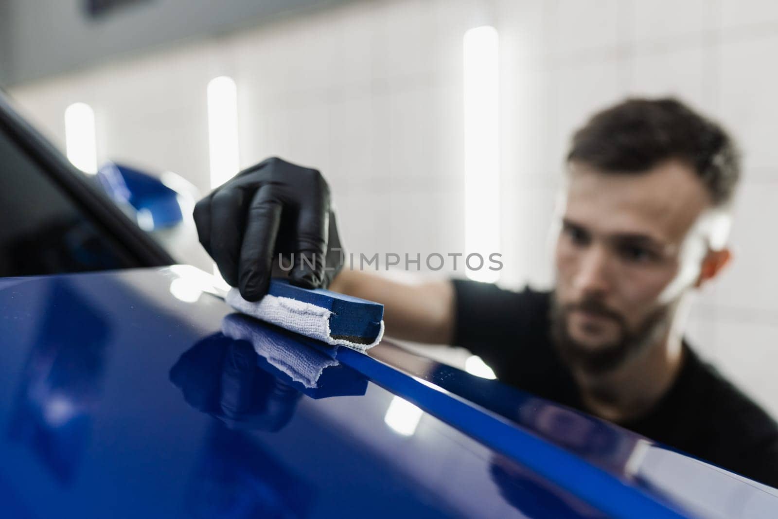 Detailing service worker applies ceramic protective liquid on car. Hand applying of nano ceramic protective coat to protect car from scratches