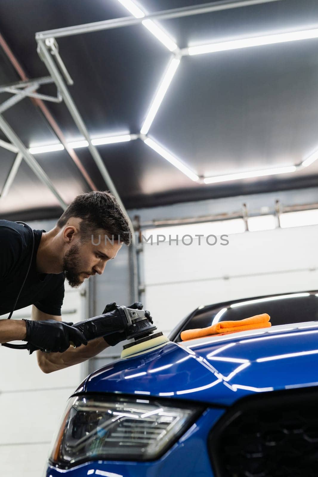 Car polishing with orbital polisher for remove scratches. Worker of detailing auto service making final polishing for car. by Rabizo