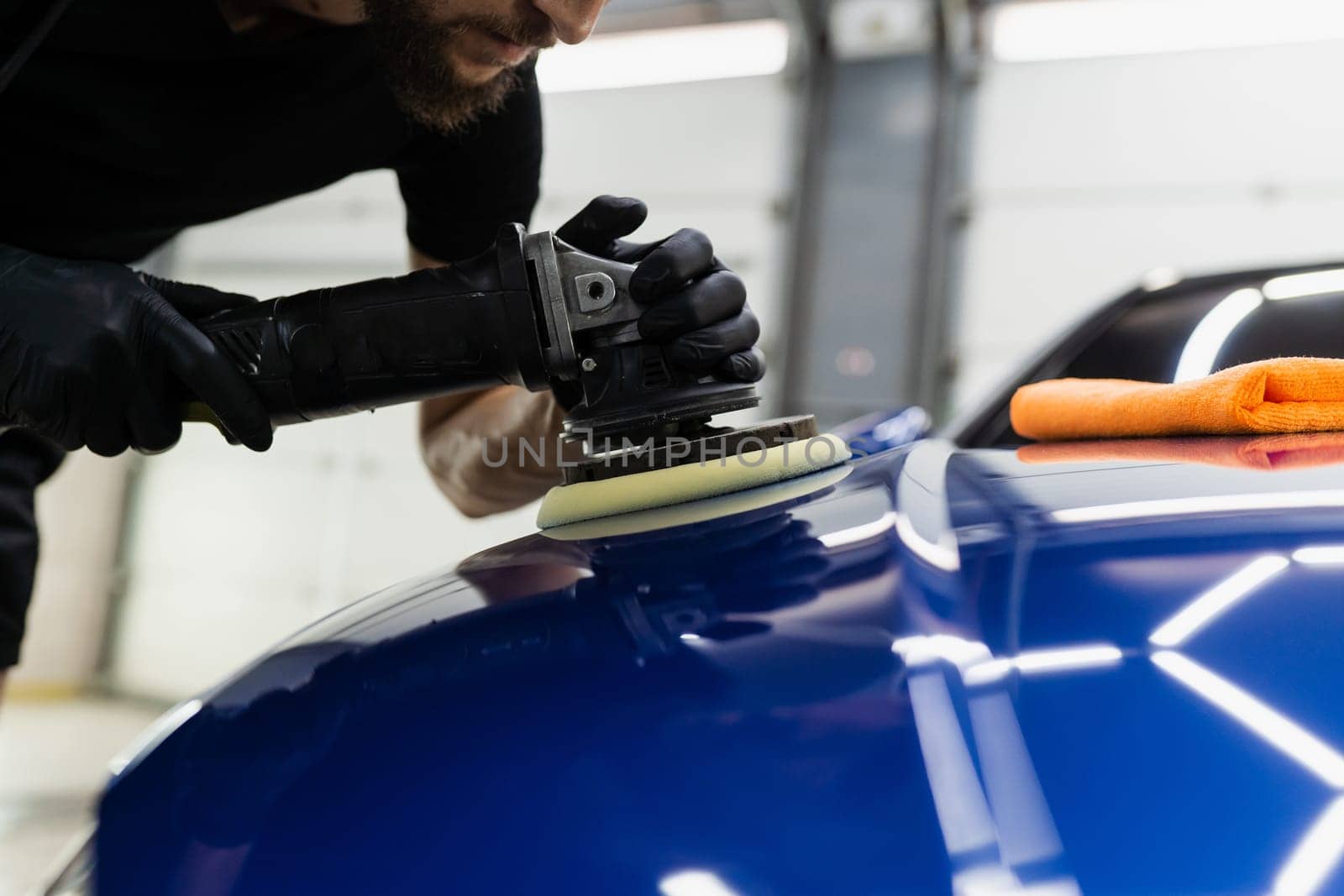 Abrasive paste car polishing with orbital polisher for remove scratches. Worker of detailing auto service making final polishing for car. by Rabizo