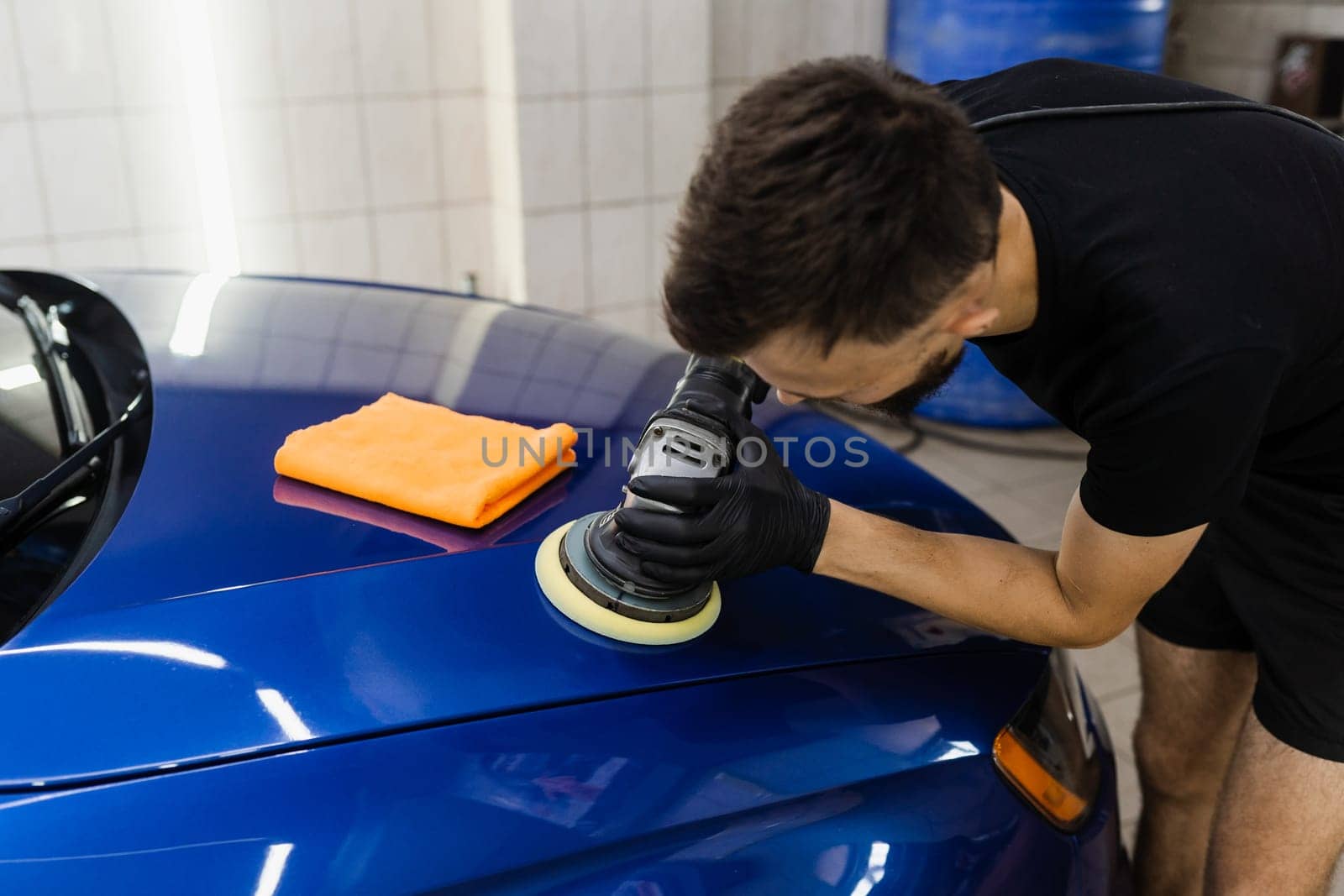Abrasive paste car polishing with orbital polisher for remove scratches. Worker of detailing auto service making final polishing for car
