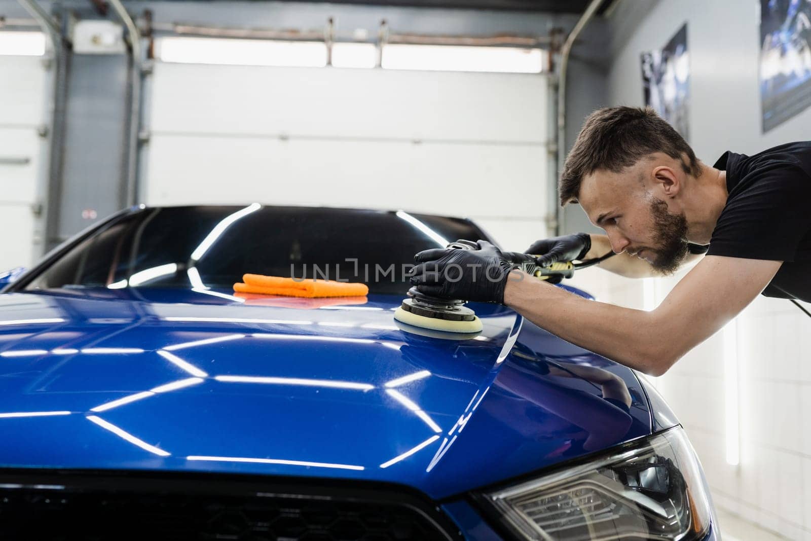 Hard wax car polishing with orbital polisher for remove scratches close-up. Working process in detailing auto service