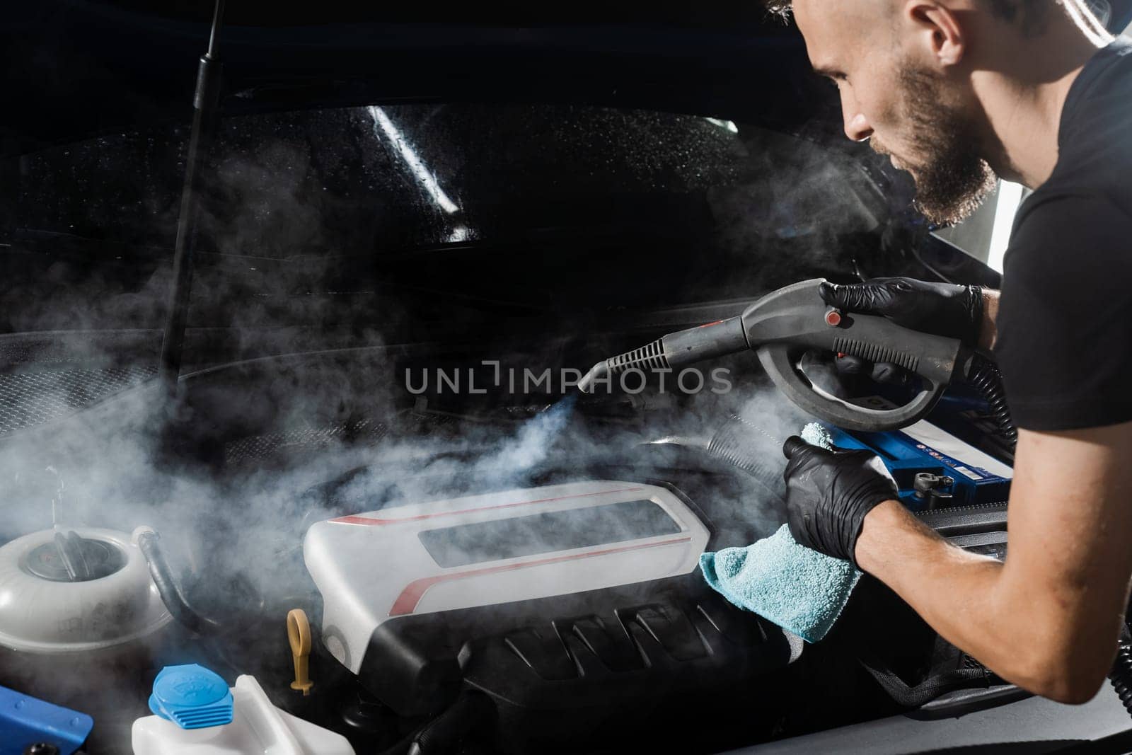Process of steam cleaning car engine from dust and dirt. Steaming washing of motor of auto in detailing auto service