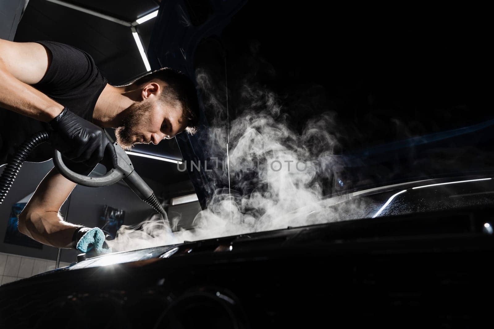 Process of steam cleaning car engine from dust and dirt. Steaming washing of motor of auto in detailing auto service