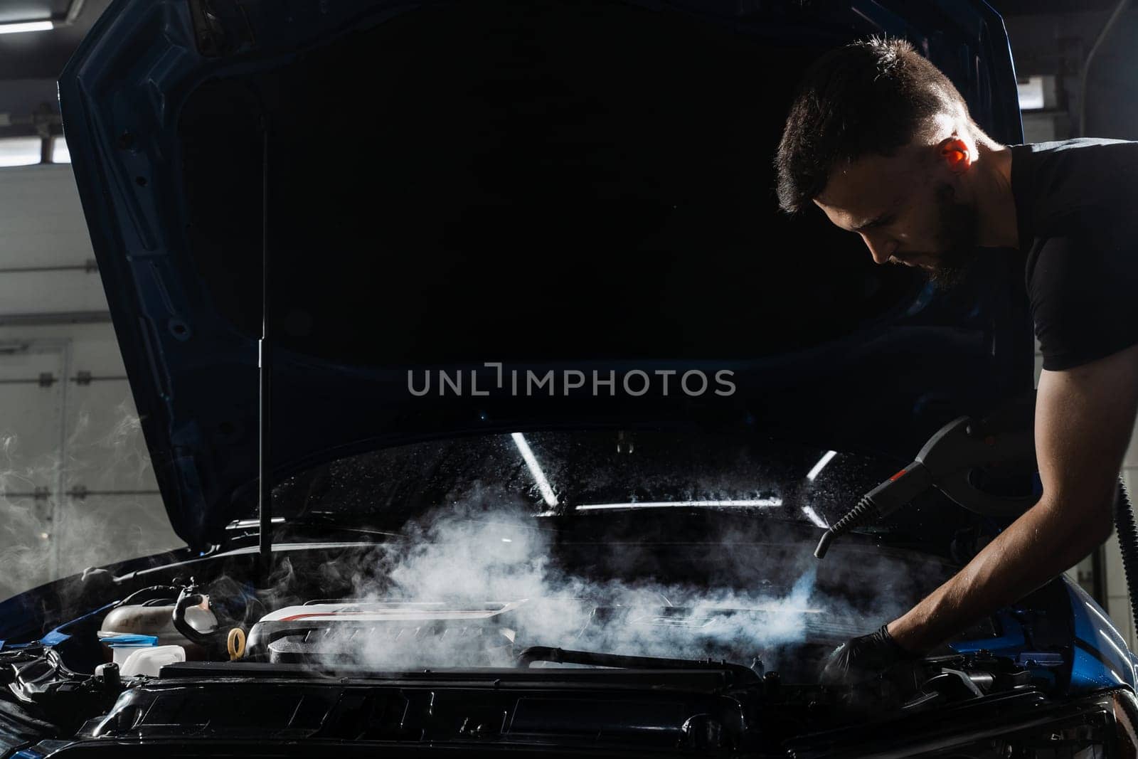 Steaming washing of motor of auto in detailing auto service. Process of steam cleaning car engine from dust and dirt. by Rabizo