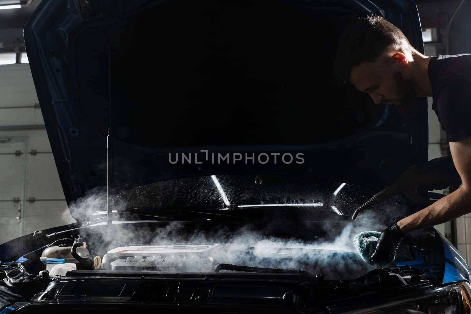 Steaming washing of motor of auto in detailing auto service. Process of steam cleaning car engine from dust and dirt