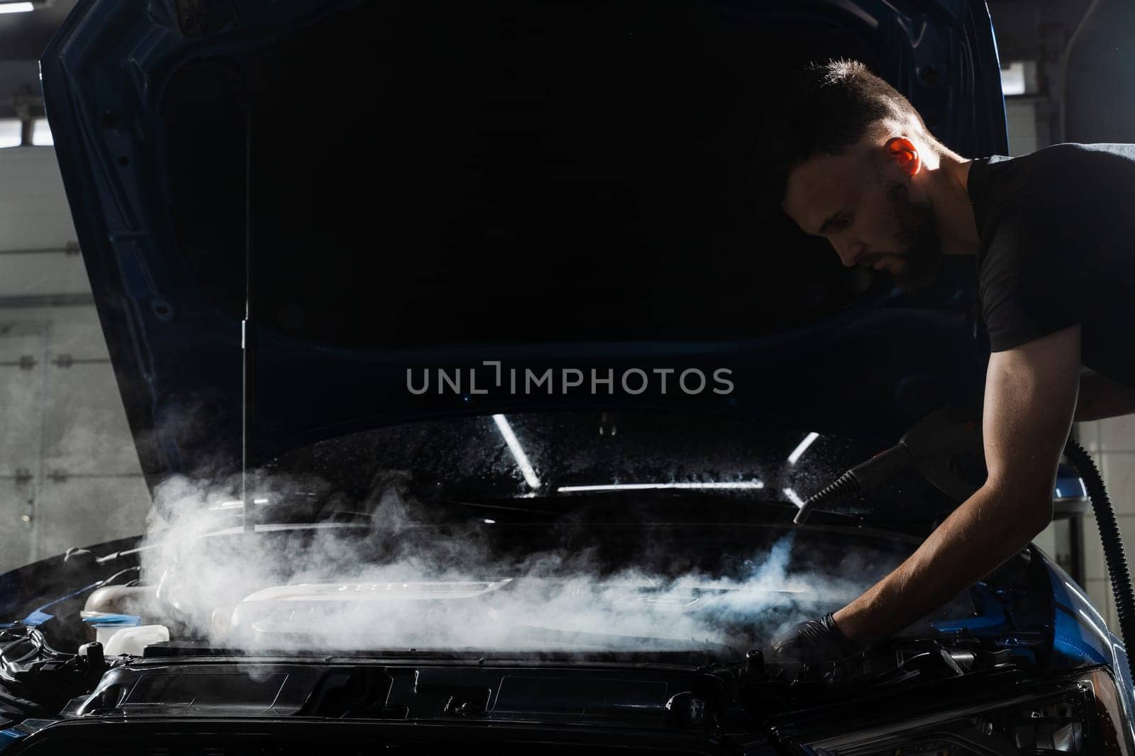 Steaming washing of motor of auto in detailing auto service. Process of steam cleaning car engine from dust and dirt. by Rabizo