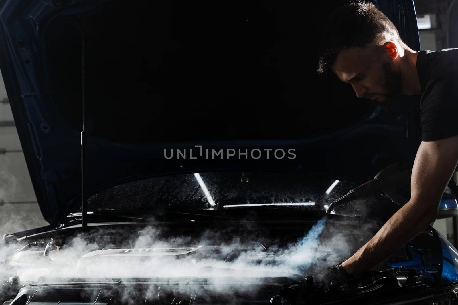 Steaming washing of motor of auto in detailing auto service. Process of steam cleaning car engine from dust and dirt. by Rabizo