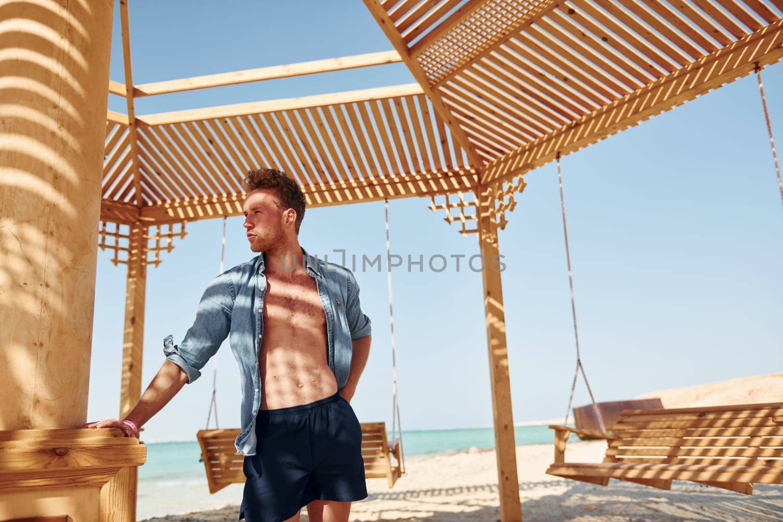 Shows body. Young european man have vacation and enjoying free time on the beach of sea.