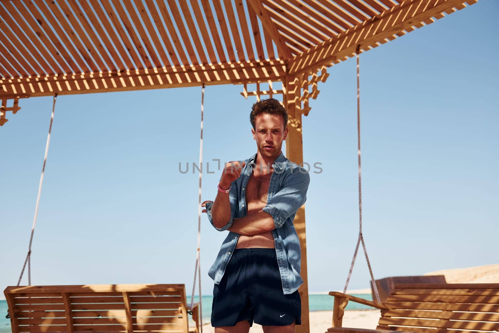 Shows body. Young european man have vacation and enjoying free time on the beach of sea.