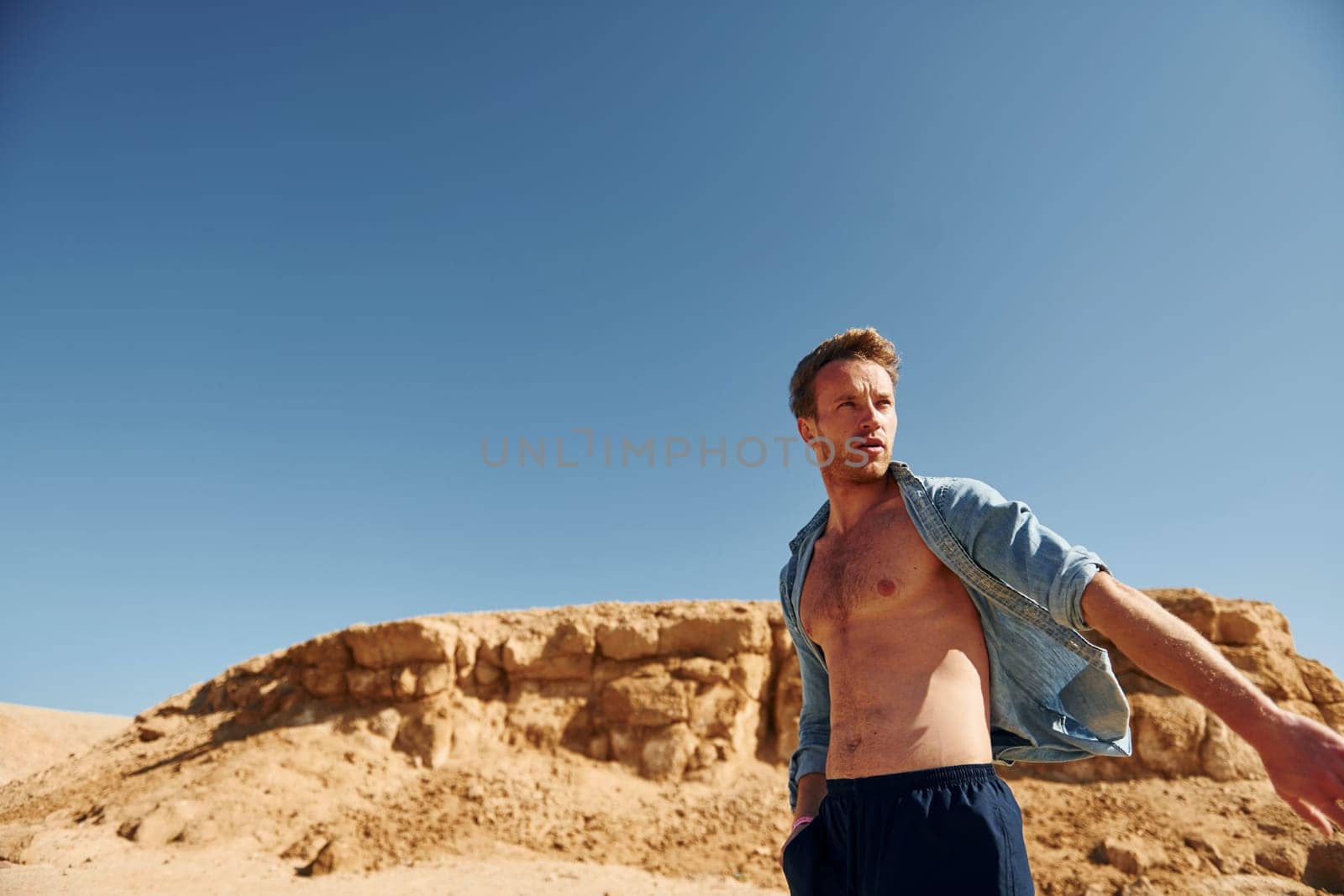 Shows body. Young european man have vacation and enjoying free time on the beach of sea.