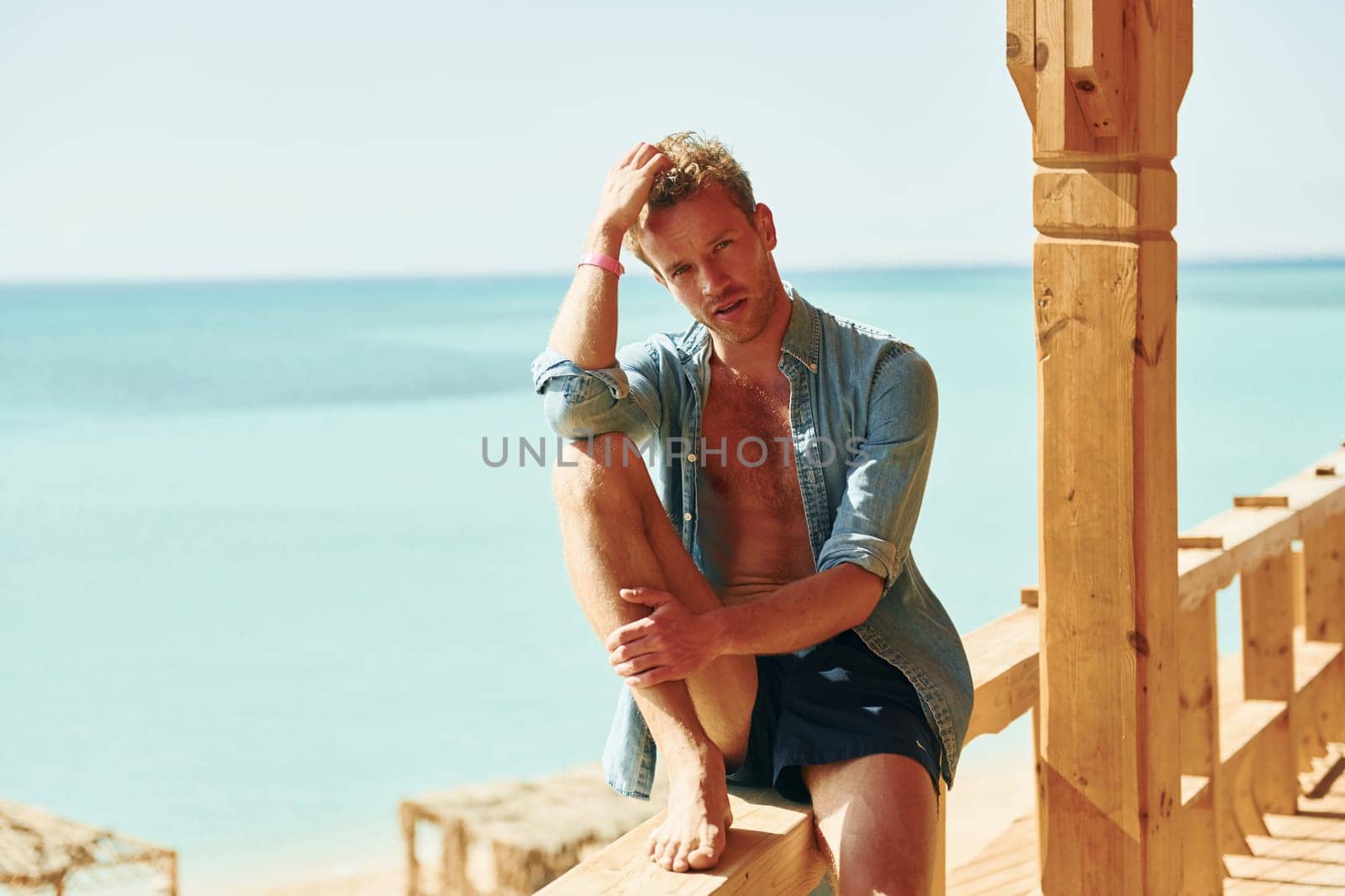 Wooden building. Young european man have vacation and enjoying free time on the beach of sea.