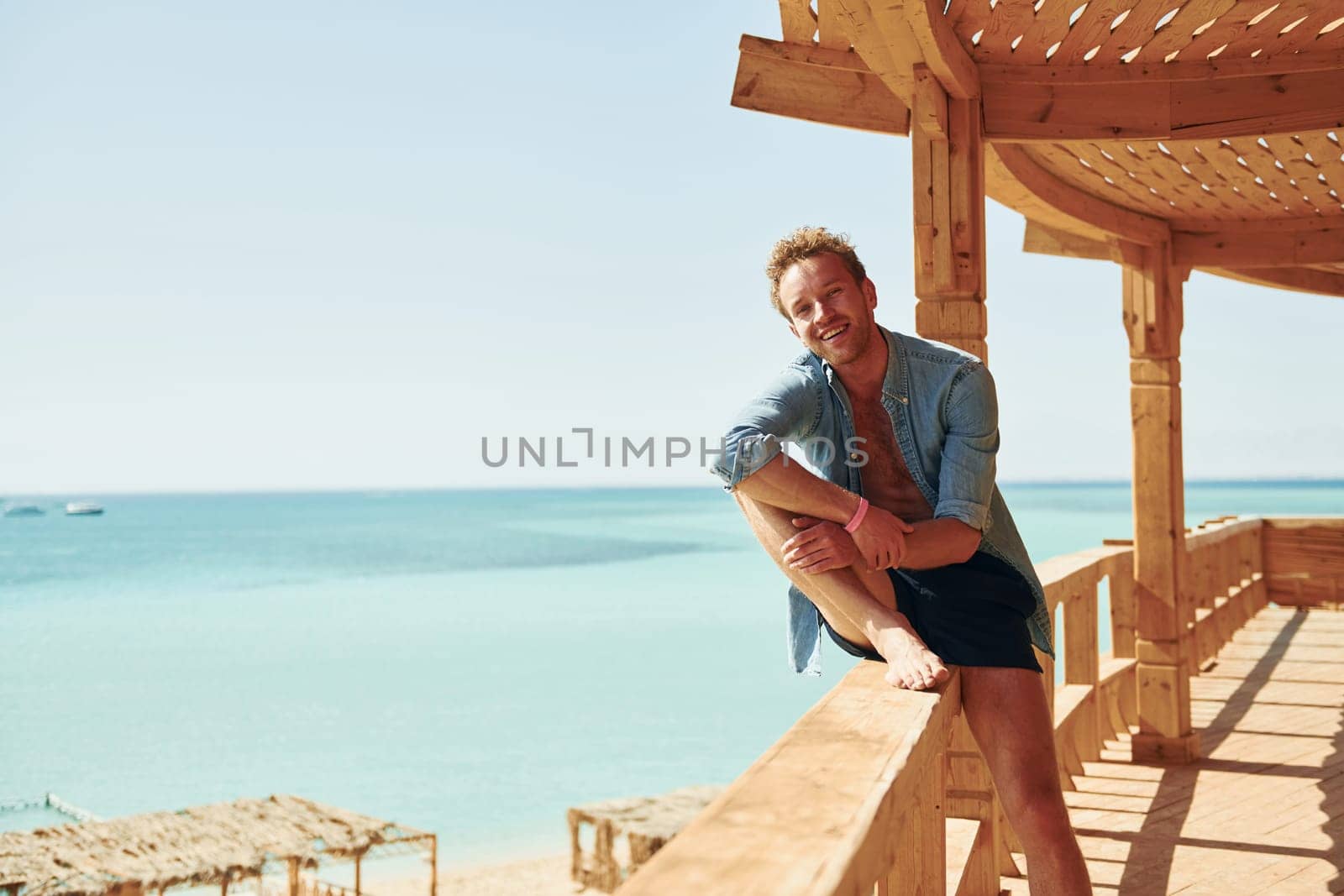 Wooden building. Young european man have vacation and enjoying free time on the beach of sea.