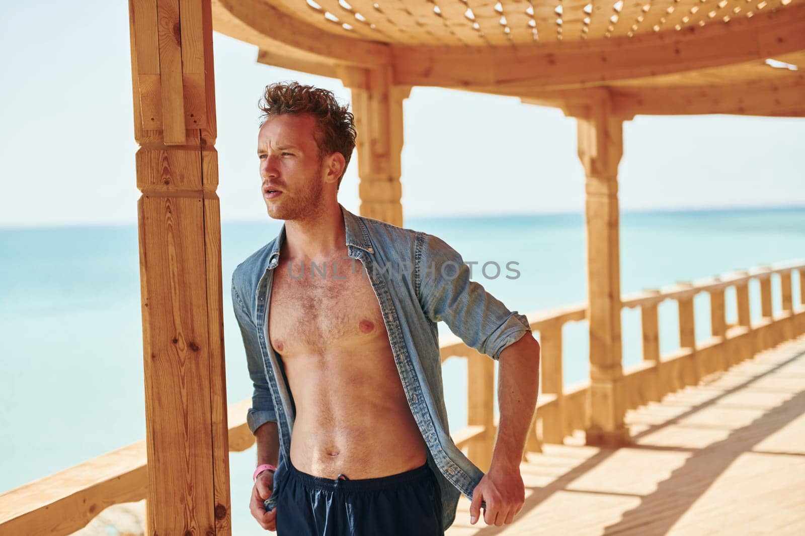 Wooden building. Young european man have vacation and enjoying free time on the beach of sea.