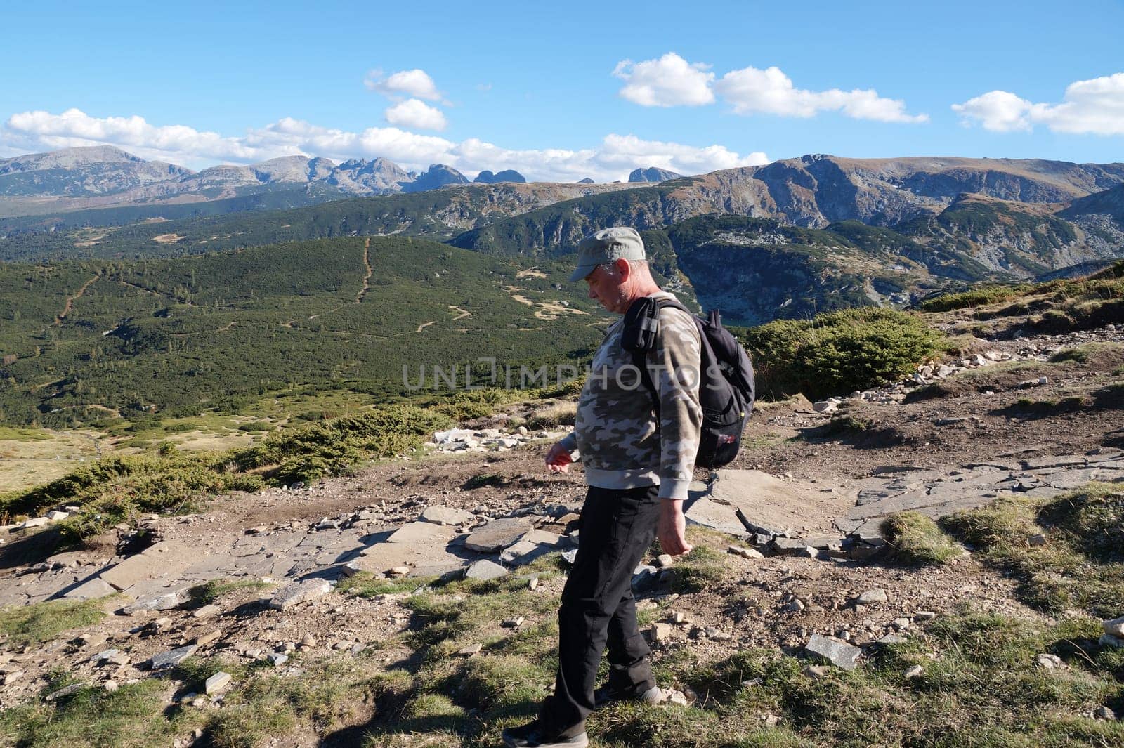 a man with a backpack walks along a mountain path.