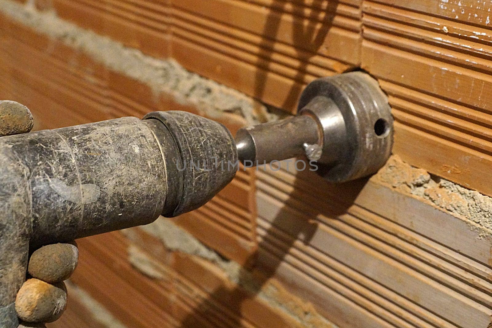 drilling a hole for an outlet in a brick wall with a puncher close-up.