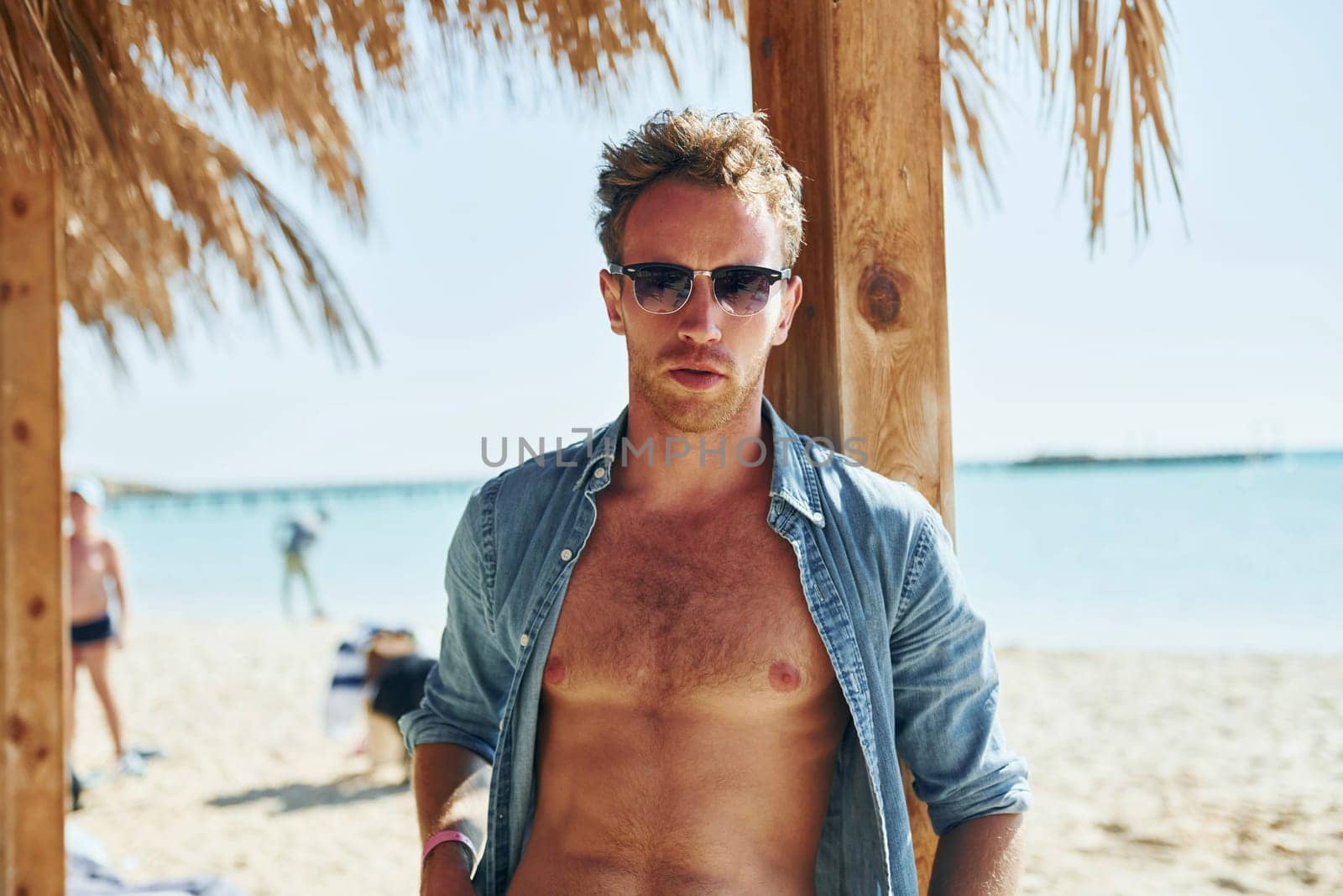 Posing for a camera. Young european man have vacation and enjoying free time on the beach of sea.