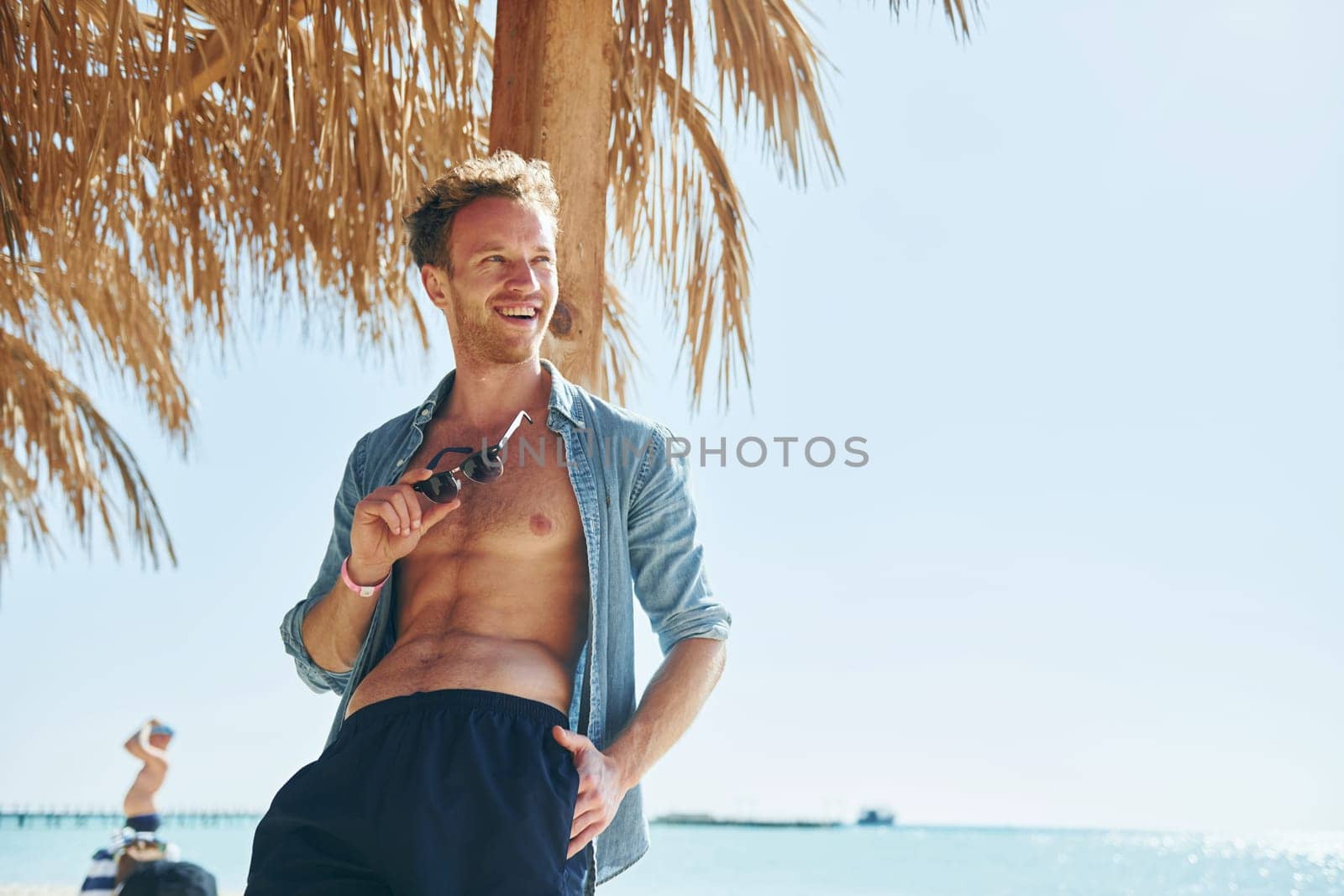 Posing for a camera. Young european man have vacation and enjoying free time on the beach of sea by Standret