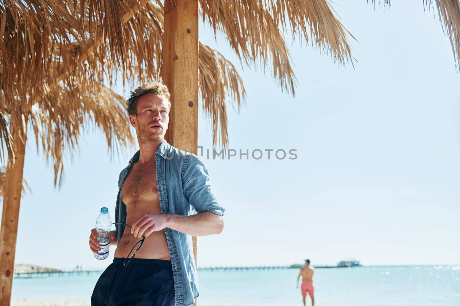 Posing for a camera. Young european man have vacation and enjoying free time on the beach of sea by Standret