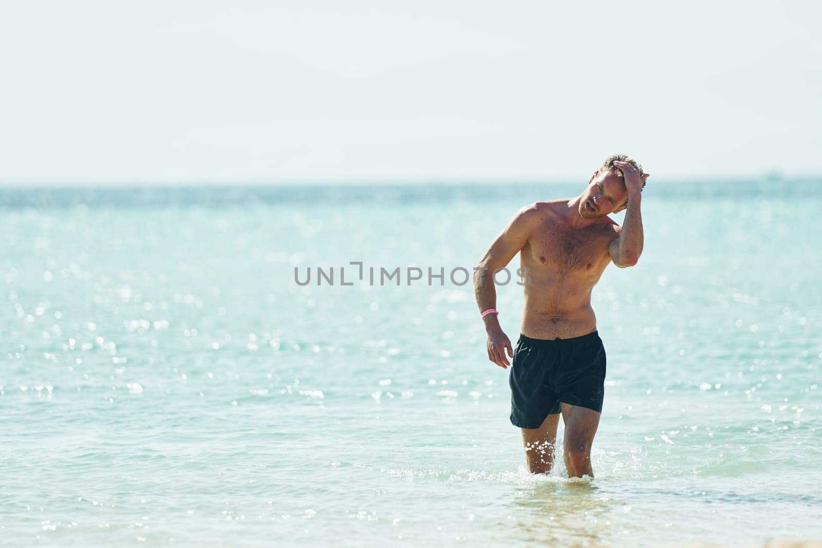 Clear water. Young european man have vacation and enjoying free time on the beach of sea.