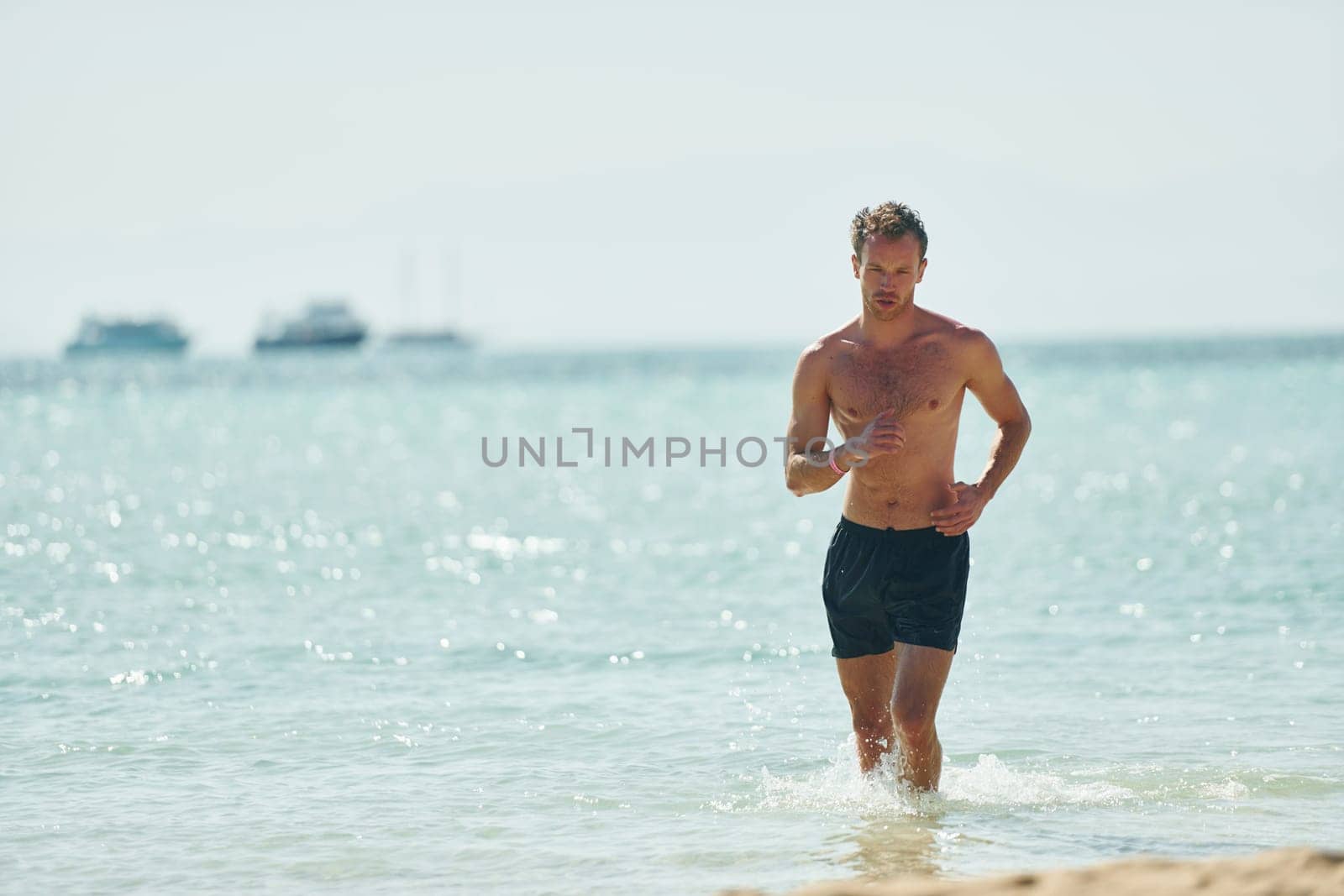 Clear water. Young european man have vacation and enjoying free time on the beach of sea.