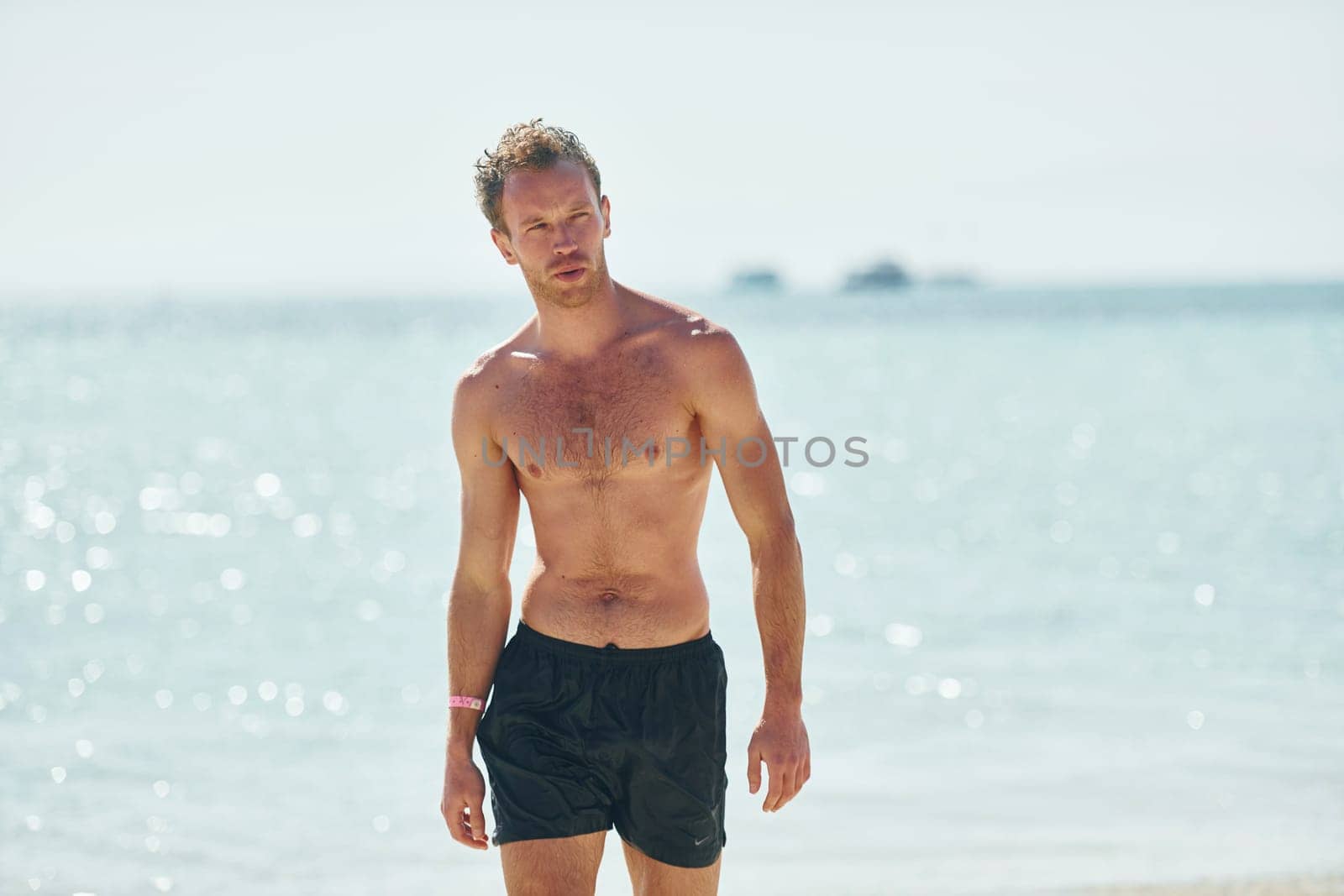 Clear water. Young european man have vacation and enjoying free time on the beach of sea by Standret