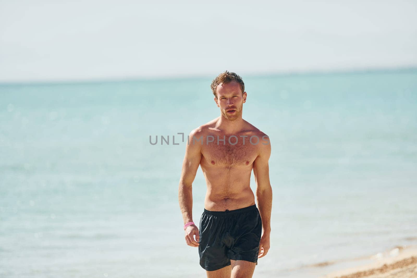 Clear water. Young european man have vacation and enjoying free time on the beach of sea.