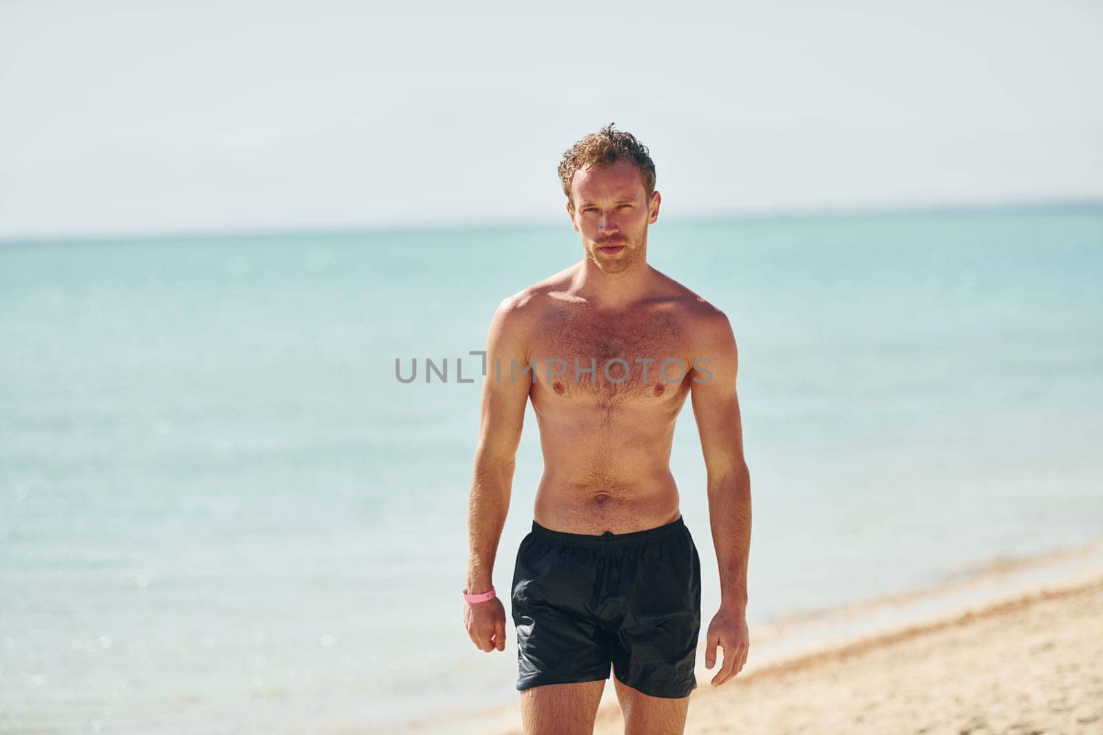 Clear water. Young european man have vacation and enjoying free time on the beach of sea.