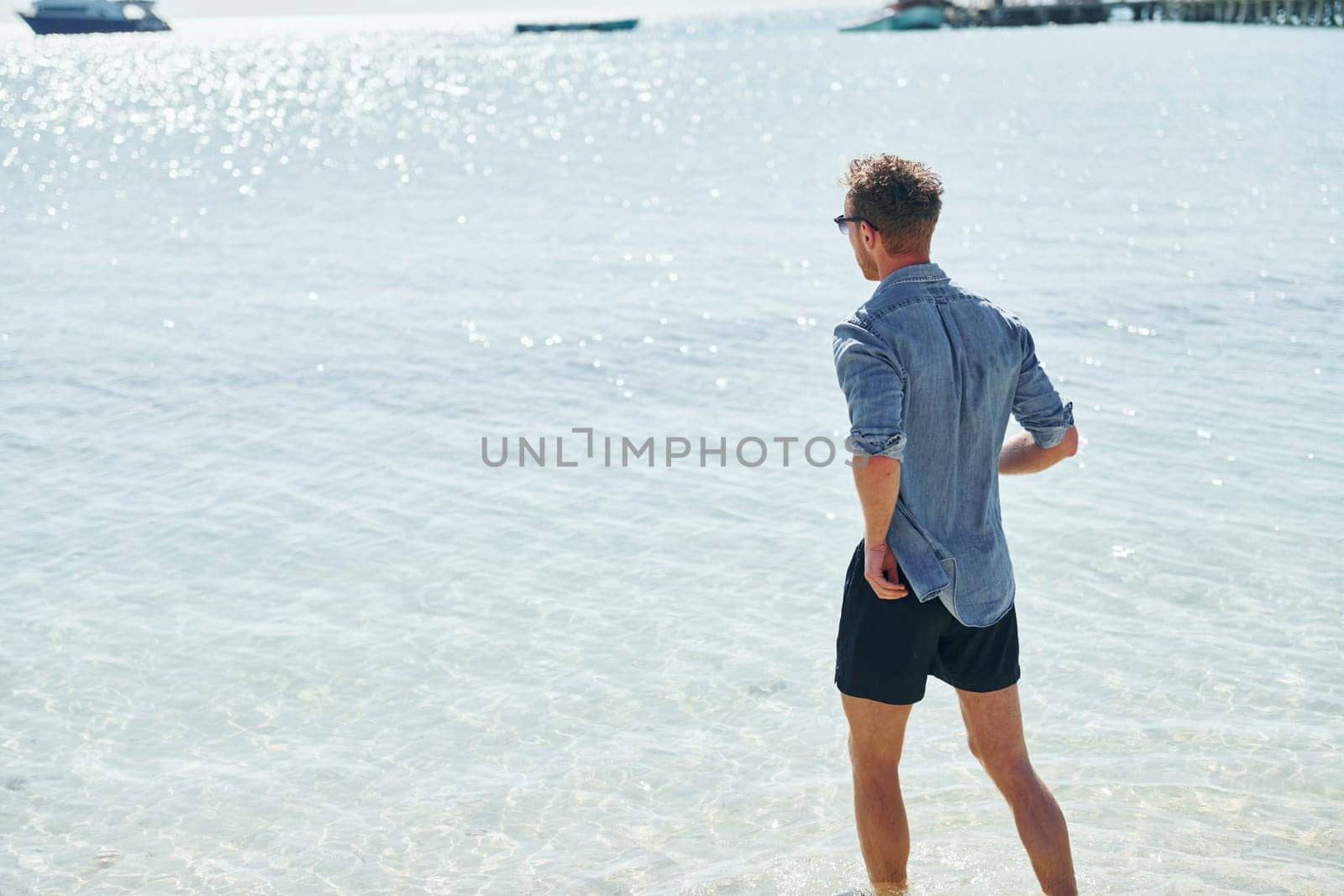 Clear water. Young european man have vacation and enjoying free time on the beach of sea by Standret