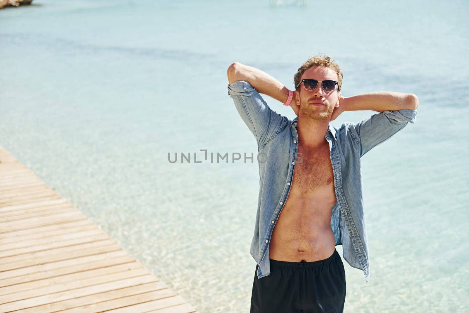 In sunglasses. Young european man have vacation and enjoying free time on the beach of sea.