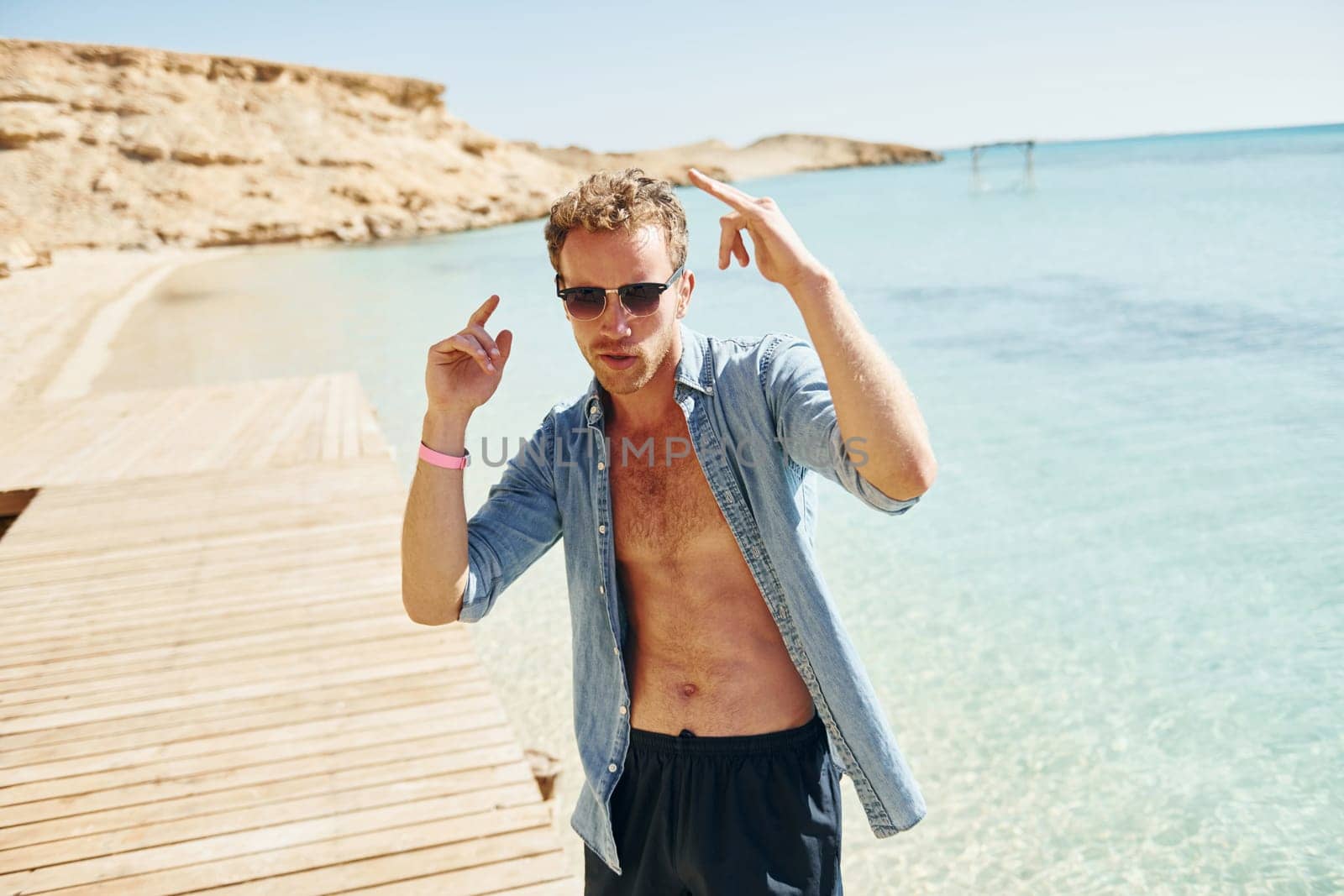 In sunglasses. Young european man have vacation and enjoying free time on the beach of sea.